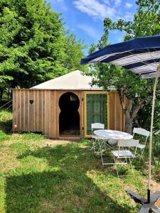 a shed with a table and chairs in a yard at Tente-Cabane en Quercy in Planioles