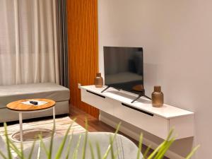 a living room with a tv on a white table at Comfort Inn Hotel in Kukës