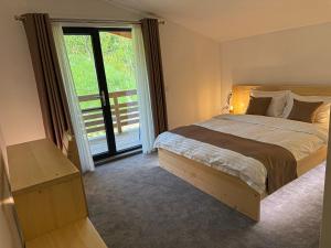 a bedroom with a large bed and a large window at ZAMURA Casa in Bozioru
