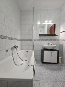 a white bathroom with a tub and a sink at Diamant Apartmanház in Eger +68 photos