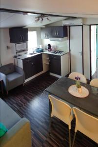 a kitchen and living room with a table and chairs at Mobil home Camping Les Embruns 4 étoiles in Lège-Cap-Ferret