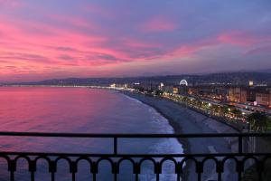a view of a beach at night with a pink sky at Hotel Suisse in Nice