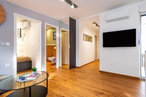 ein Wohnzimmer mit einem Tisch und einem TV an der Wand in der Unterkunft Villa Royal Green Resort in Nona