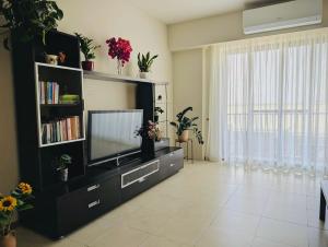 a living room with a tv and a book shelf at Sunset Haven Manikata - Walking distance to Golden Bay in Manikata