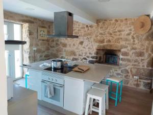 a kitchen with a stove and a stone wall at Casa Castro in Lamas