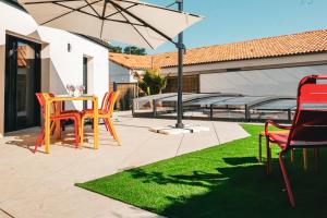 eine Terrasse mit Stühlen und einem Tisch mit einem Sonnenschirm in der Unterkunft Villa des Hérondais avec piscine - idéal familles - 8 personnes in Jard-sur-Mer