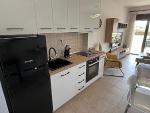 a kitchen with a black refrigerator and white cabinets at Domus Afitos in Afitos