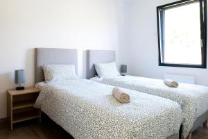 zwei Betten in einem weißen Zimmer mit Fenster in der Unterkunft Villa des Hérondais avec piscine - idéal familles - 8 personnes in Jard-sur-Mer + 35 Fotos