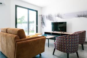 ein Wohnzimmer mit zwei Stühlen und einem Fernseher in der Unterkunft Villa des Hérondais avec piscine - idéal familles - 8 personnes in Jard-sur-Mer
