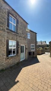 - un bâtiment en briques avec une porte et des fenêtres vertes dans l'établissement Wisteria Cottage, à Eyam