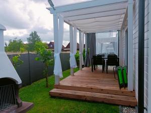 a wooden deck with a table and a white canopy at Domki letniskowe Czapli9 Domki Rewal Apartamenty in Rewal