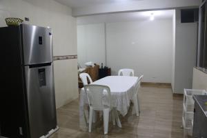 cocina con mesa, sillas blancas y nevera en Wasi Airport Apartment, en Lima