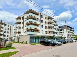 a large apartment building with cars parked in a parking lot at Apartament Wysockiego in Bielsk Podlaski