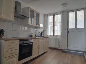 a kitchen with wooden cabinets and a stove top oven at Vue Volcans Studio de Charme Thiers Centre in Thiers