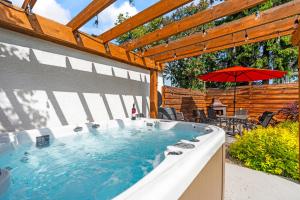 a hot tub in a patio with an umbrella at Stunning Heritage Home, Sleep 10, Hot Tub, Private Yard, Firepit, in Vernon