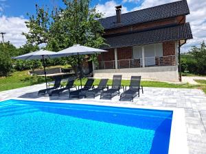 Una piscina con sillas y sombrillas al lado de una casa. en Villa Sunset, en Banja Luka
