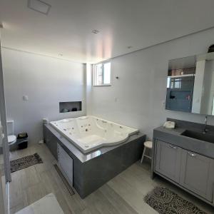 ボンビーニャスにあるResidencial Rota do Sol Bombinhas Centro 100 metros da praiaの浴槽と洗面台を備えた広いバスルーム