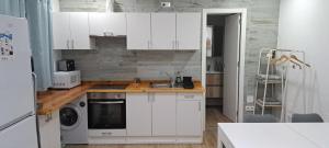 Una cocina con gabinetes blancos y un fregadero. en Poni Pisador, en Mairena del Aljarafe