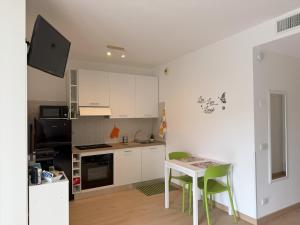 a kitchen with white cabinets and a table with green chairs at MarteNik Apartment, vicino San Raffaele e Milano in Vimodrone