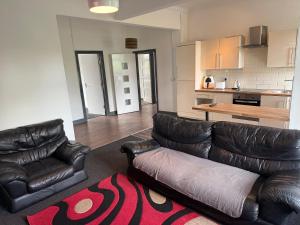 a living room with two leather couches and a kitchen at Lux spacious 3BR entire apartment in Wakefield