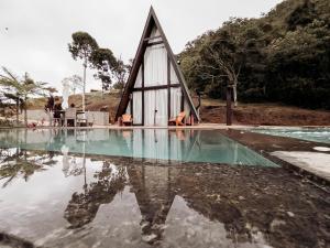 a triangular house with its reflection in the water at Turisfri Resort in Nova Friburgo