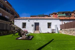 a white house with a green yard with a tree at Casa Postiguillo in Manzanares el Real
