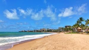a beach with palm trees and the ocean and buildings at Vacanze - Jardim Tropical in Maceió