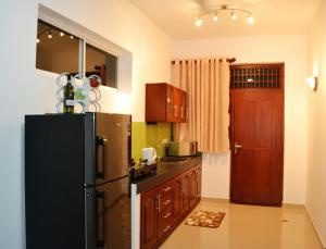 a kitchen with a black refrigerator and wooden cabinets at Orchidee Apartments in Mount Lavinia