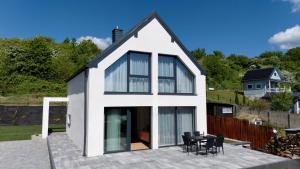 a house with white walls and windows on a patio at Domek na Rybackiej in Swarzewo