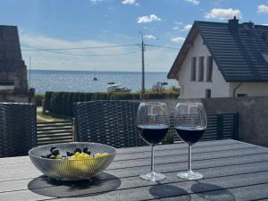 two glasses of wine and a bowl of fruit on a table at Domek na Rybackiej in Swarzewo