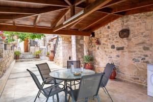 a patio with a table and chairs and a stone wall at Traditional stone house Ariadne near Matala beach in Petrokefálion