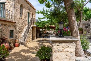 a stone building with a tree and a street at Traditional stone house Ariadne near Matala beach in Petrokefálion