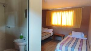 a small bathroom with two beds and a sink at Casa de Primo in Puno