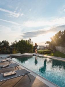 a woman is standing next to a swimming pool at Villa Solaria in Sveti Stefan