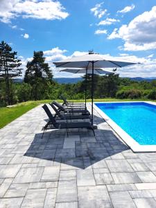 Un grupo de sillas y una sombrilla junto a una piscina. en Villa Sunset, en Banja Luka