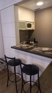 a kitchen with two chairs and a counter with a microwave at 154apartamento lindo no itaim bibi in Sao Paulo