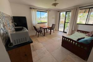 a living room with a bed and a tv and a table at Aldeias Guajiru Apart in Trairi