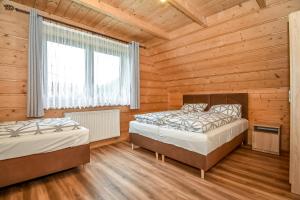 twee bedden in een kamer met houten wanden bij Domki u Wilka in Poronin