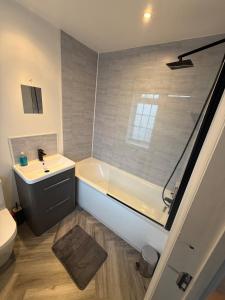 a bathroom with a tub and a sink and a toilet at Spacious 3 bed house garden & parking sleeps 5 in Belvedere +2 photos