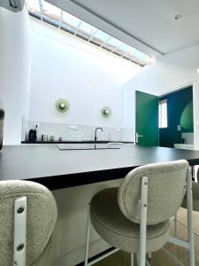 a kitchen with green and white counters and two chairs at T2 sous les toits, entre gare et centre-ville, Grands buffets in Narbonne
