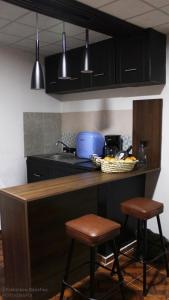 eine Küche mit schwarzen Schränken und zwei Barhockern in der Unterkunft Cozy family apartment, kitchen in Mineral del Monte