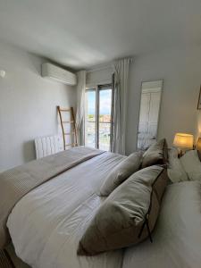 a bedroom with a large bed with pillows and a window at Marina & sea view apartment at Port Grec in Empuriabrava