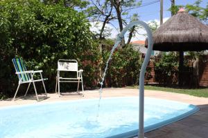 ein Springbrunnen in einem Pool mit einem Stuhl und einem Sonnenschirm in der Unterkunft Serrambi Paradise in Porto De Galinhas