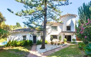 Biały dom z drzewem przed domem w obiekcie Villa Dos Palomas on the Golden Mile in Marbella w Marbelli