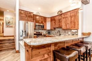 a kitchen with wooden cabinets and a large island with stools at Beaver Creek West Mountain Condo in Avon
