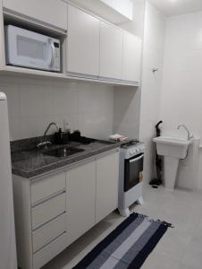 une cuisine blanche avec un évier et un micro-ondes dans l'établissement Santo Amaro ao Lado da Estação João Dias, à São Paulo