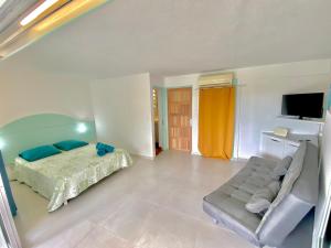 ein Schlafzimmer mit einem Bett und einer Couch in der Unterkunft Studio Petite Plage - Pieds dans l'eau in Sainte-Anne