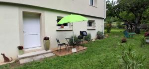 a green umbrella on a house with a table and chairs at Charmant studio Van Gogh in Chabeuil