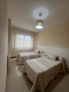 two beds in a bedroom with a window at ENV Langosteira in Fisterra
