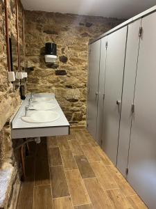 a bathroom with two sinks and a stone wall at Albergue Freixo in Palas de Rei +36 photos